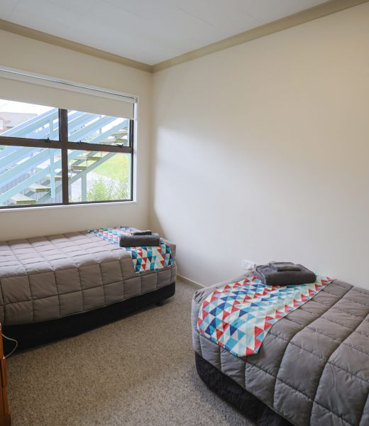 Single bed with a colourful patterned throw beside a large window in a Fitzgerald on King motel unit